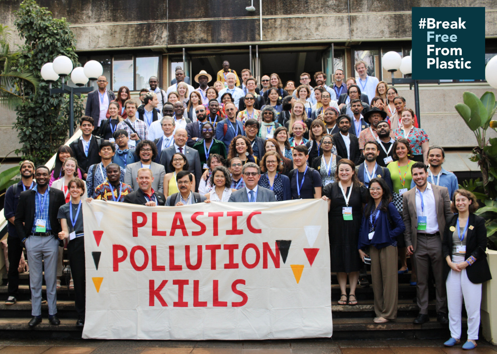 Break Free From Plastic movement members stand together holding up a banner saying Plastic Pollution Kills
